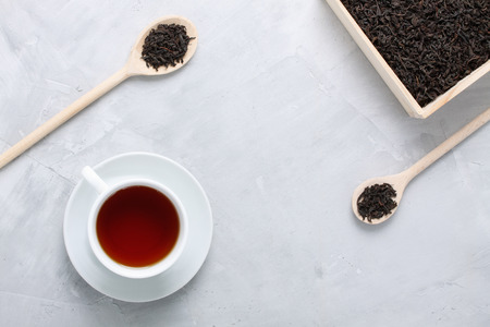 White porcelain cup of tea, wooden box, spoons on grey concrete background. Food, beverage background. Horizontal orientation, top view.の写真素材
