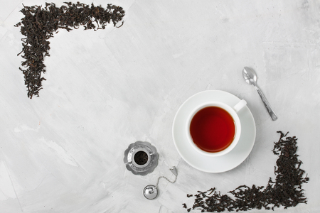 White porcelain cup of tea, small silver spoon and little silver teapot used for 
brewing loose leaf tea on grey concrete background. Food, beverage background. 
Horizontal orientation, top view.の写真素材