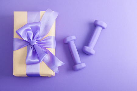 Holiday birthday party sport flat lay composition with purple dumbbells and craft gift with lilac bow on 


violet paper background. Top view, horizontal orientationの写真素材