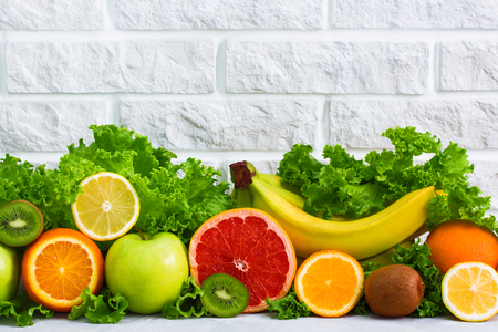 Healthy food fruits grapefruit, lemon, kiwi, apple, banana, orange, green 


salad background on white painted brick wall. Concept healthy eating diet 


plan detox sports nutrition.の写真素材