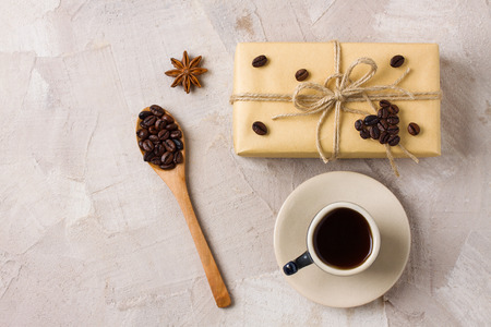 Blue coffee cup, craft gift box twine coffee heart shape decoration, wooden spoon with coffee beans, anise on beige concrete background. Gift decor idea for coffee lovers. Place for copy space text.の写真素材