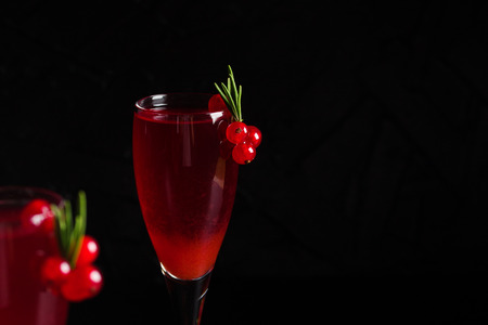 Glass of redcurrant wine drink juice decorated with rosemary and berries on dark wooden...