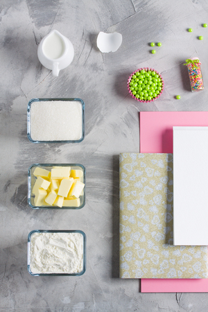Cooking baking flat lay background with eggs, butter, flour, sugar, milk, colored sprinkling, eggshell, notebook for recipe. Concept cooking baking for kids.の写真素材