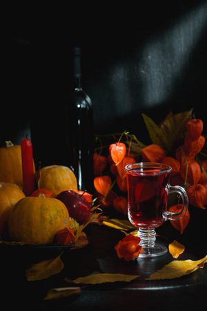 Glass of wine tea juice red drink dry leaves physalis. Halloween, thanksgiving, autumn still 
life composition background, vertical orientation, close up.の写真素材