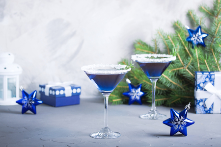 Christmas composition with martini drinks with rosemary and sugar decoration, fir-trees, stars, 


candle lamp, gift box in blue colors, gray concrete background. Winter holiday, New Year party 


concept.の写真素材