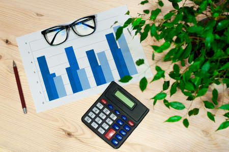 workstation of an accountant or economist, top view of the calculator, graphs, glasses and penの写真素材