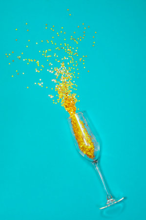 new year, Christmas, confetti in the form of stars pour out of a recumbent glass of champagne on a blue backgroundの写真素材