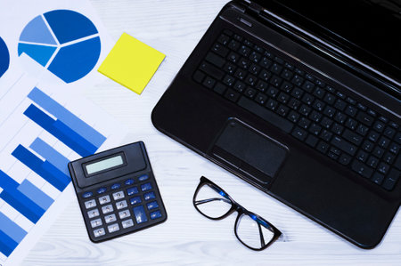 office workstation with computer, graphs, calculator and glasses. Top viewの写真素材