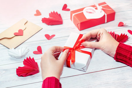 girl ties a red ribbon on a gift box, valentines dayの写真素材