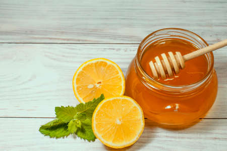 fresh honey in a transparent jar on a wooden background and lemon with mint, healthy lifestyleの写真素材