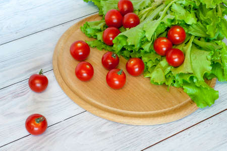 fresh cherry tomatoes and lettuce salad lie on the chopping boardの写真素材
