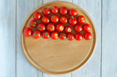 fresh cherry tomatoes lie on a wooden board for cutting on a wooden backgroundの写真素材