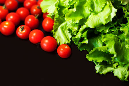 green lettuce and cherry tomatoes on a dark backgroundの写真素材