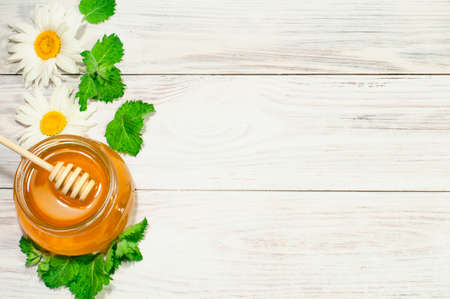 fresh honey in a jar on a wooden background with daisies, banner, advertising. High quality photo
