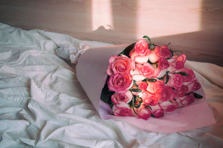 a bouquet of beautiful pink roses on a crumpled bed in the sun.の写真素材