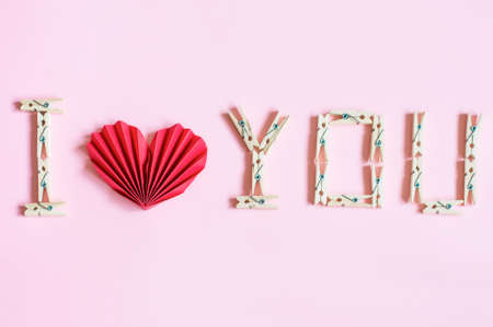 on a pink background, an inscription in the form of recognition lined with wooden clothespins and a red heartの写真素材