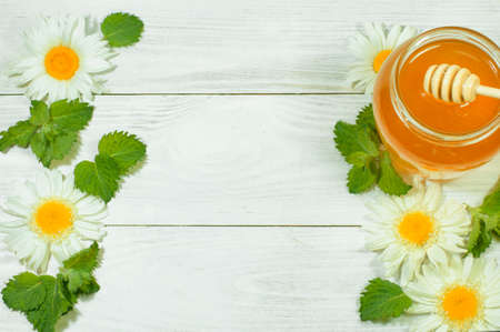 fresh honey in a jar on a wooden background with daisies, banner, advertisingの写真素材