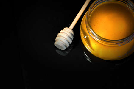 fresh honey in a jar and a honey spoon on a black backgroundの写真素材