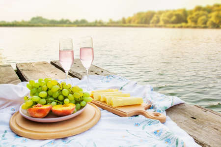 delicious food with wine for a romantic picnic by the river, summer, dawnの写真素材