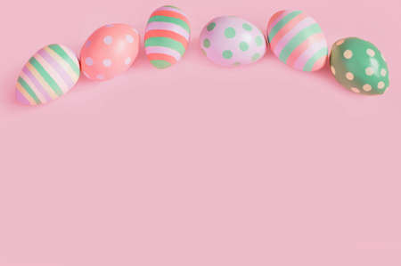 Easter multi-colored eggs on a pink background lie in a rowの写真素材