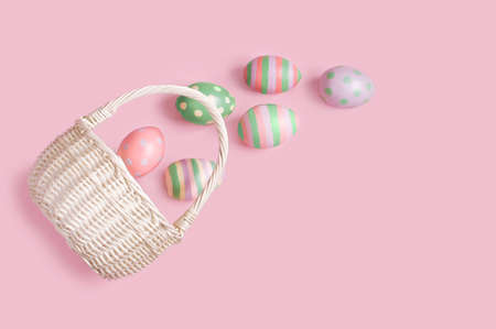 a wicker basket lies on a pink background and Easter eggs near it, Easterの写真素材