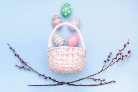 basket with Easter eggs and branches of flowering willow on a blue backgroundの写真素材