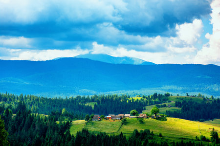 sunny landscape of green hills and blue sky and mountains in the backgroundの写真素材