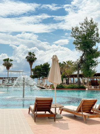 Relaxation area near the pool with sun loungers and closed umbrellas, fountain and bridgesの写真素材