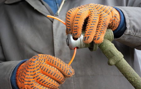 Male hands in gloves setting up manual lawn mower to clean grassの写真素材