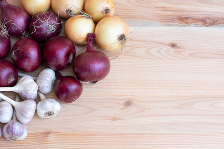 Red and yellow onions with garlic lie on a wooden background harvest. Copy spaceの写真素材