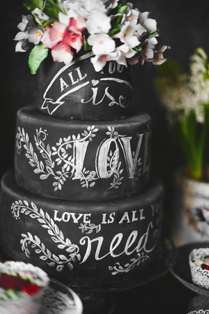 Stylish black wedding cake with flowers and the lettering love at candy barの写真素材