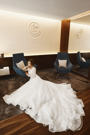 Elegant and beautiful model girl in a fashionable lace dress with nude back sits on the floor at the luxury interiorの写真素材