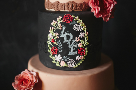 Stylish four parts wedding cake with flowers and the lettering love on the dark tableの写真素材