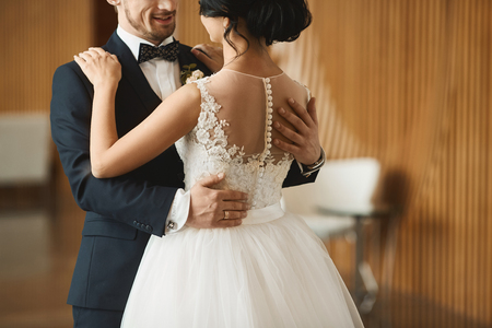 Fashionable dancing couple, handsome young man in the stylish suit and beautiful brunette model girl with wedding hairstyle in the white lace dressの写真素材