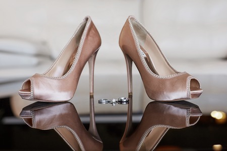 Close up view of luxury platinum wedding rings with diamonds and female wedding shoes before the wedding ceremonyの写真素材