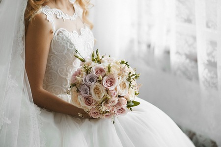 A beautiful wedding bouquet of fresh colorful flowers in the hands of sexy beauty in a wedding dressの写真素材