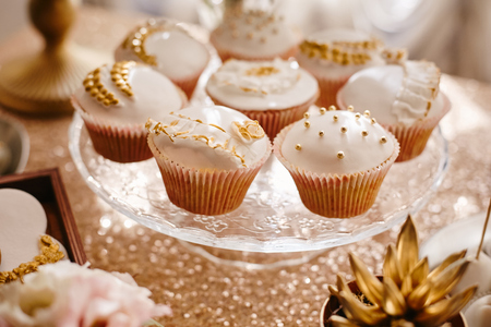 Delicious wedding cupcakes with glaze with gold details at the wedding buffetの写真素材