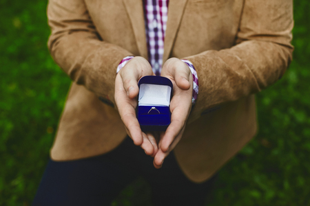 Box with stylish gold wedding rings in male hands of the handsome young man, proposal of marriageの写真素材