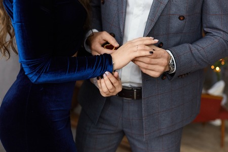 Fashionable couple of lovers, handsome young businessman in the stylish suit and beautiful model girl with perfect body in blue tight dress holding handsの写真素材