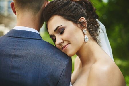 Portrait of beautiful plus size model woman with stylish wedding hairstyle in a fashionable dress leans on her groom. Beautiful model girl in wedding dress posing with her man before wedding ceremonyの写真素材