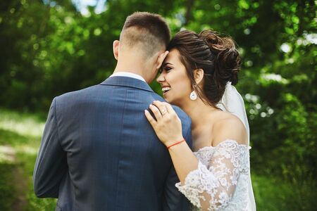 Happy plus size model woman with stylish wedding hairstyle in a fashionable dress laugh and hug handsome groom. Beautiful model girl in wedding outfit posing with the groom before the wedding ceremonyの写真素材