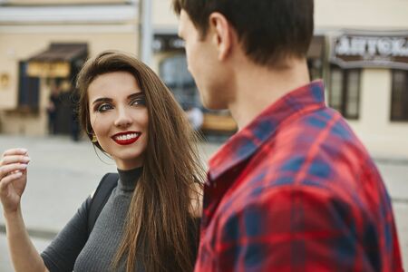 Young beautiful couple of lovers at the dating. Young woman with a perfect white smile and red lips and a handsome young man spending time together in the cityの写真素材