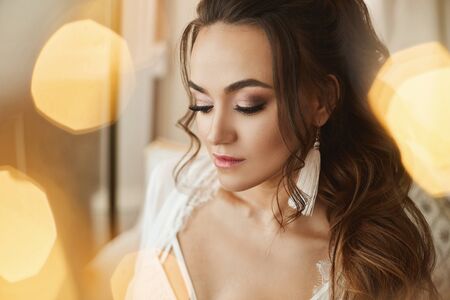 Young woman with perfect face skin, makeup and bridal hairstyle posing with closed eyes on unfocused background. Wedding preparationの写真素材