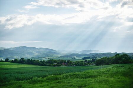 Rural landscape somewhere in Europe. Countryside farm, trees, green field, sunlight and cloud