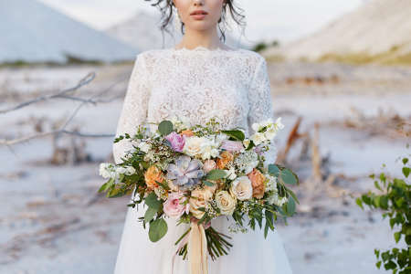 A luxury bouquet of exotic flowers in the hand of a young woman in a lace dressの写真素材