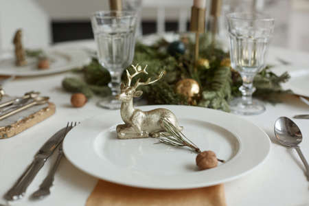 Christmas or New Years celebration party table setting. Plate with golden deer, cutlery and glassesの写真素材