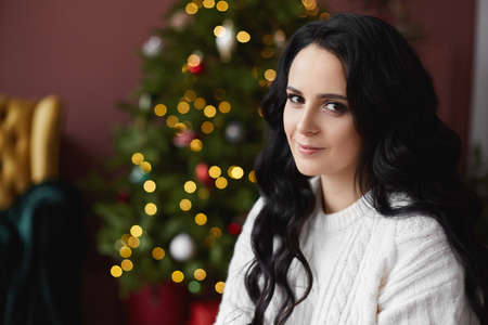 Portrait of a young brunette woman with festive Christmas lights in the background