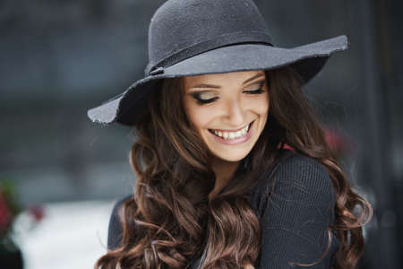 Closeup fashion portrait of a young model girl with trendy makeup wearing black fashionable hat posing outdoorsの写真素材