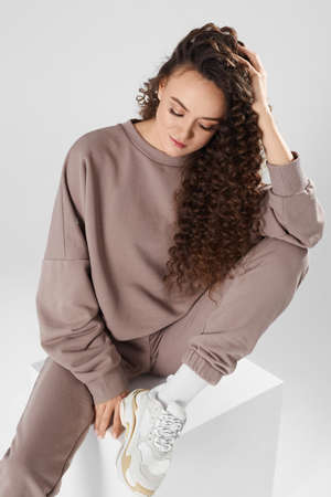 Cropped portrait of a model girl with trendy hairstyle wearing a blanket sweatshirt over white backgroundの写真素材