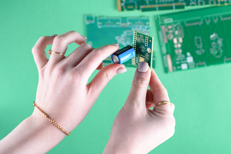 The woman technician is assembling a capacitor on the Circuit Board. The concept of computer,...